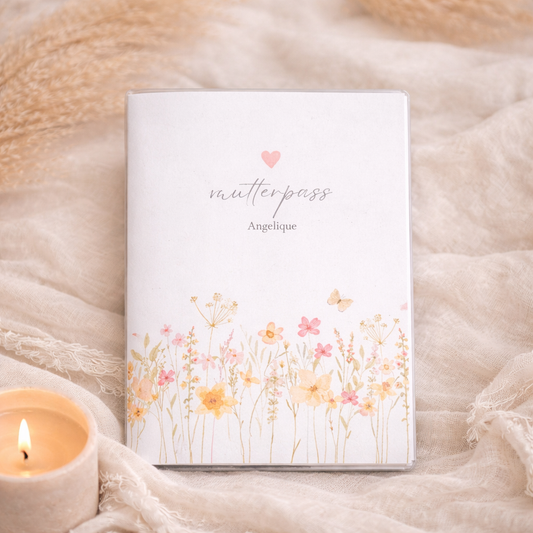 Personalisierte Mutterpass Hülle mit zarter Wiesenblumen Aquarell Illustration im Boho Stil, individuell mit Namen personalisiert, fotografiert auf beigem Stoffhintergrund.
